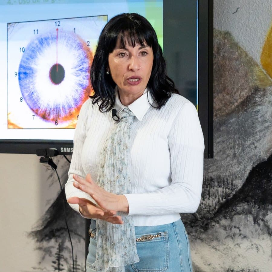 Guadalupe Martín explicando el uso de la gráfica iridológica junto a una pantalla con un iris ampliado.